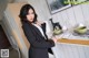 A woman in a black suit standing next to a table.