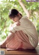 A woman sitting on the ground with her head in her hands.