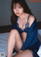 A woman in a blue lingerie sitting on a bed.