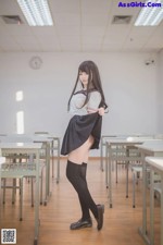 A woman in a school uniform standing in a classroom.