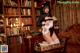 A woman in a maid outfit sitting on a chair in front of a bookcase.