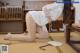 A woman in a white dress is kneeling on the floor.