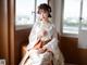 A woman in a white and orange hanbok sitting on a chair.